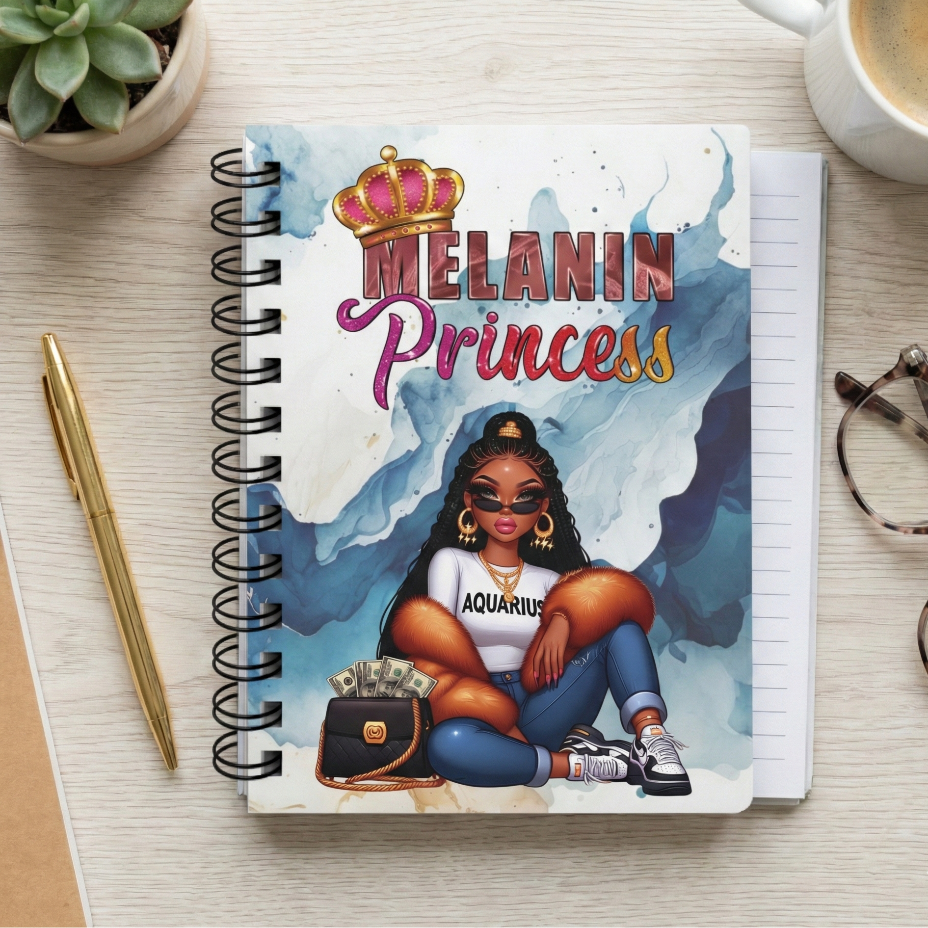 Notebook with 'Melanin Princess' design on a desk with a cup of coffee, pen, and glasses.